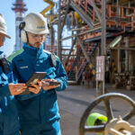un hombre y una mujer con ropa laboral en una planta industrial chequeando documentos